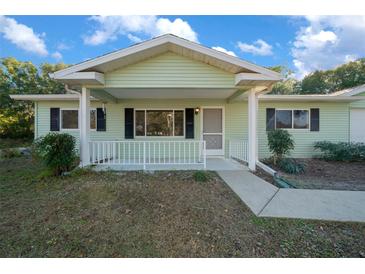 Ranch style home with light green siding, covered porch and landscaped yard at 7556 Sw 112Th Ln, Ocala, FL 34476