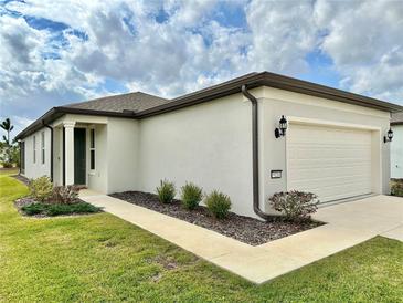 Single-story home with a white exterior, two-car garage, and landscaped front yard at 9326 Sw 52Nd Loop, Ocala, FL 34481