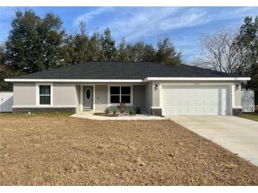 Newly constructed one-story home with gray exterior, white garage door, and landscaping at 14351 Se 34Th Ct, Summerfield, FL 34491