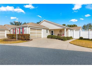 Cute 1 story home with attached garage, landscaped yard, and white vinyl fence at 1941 Yellow Pine Pl, The Villages, FL 32162