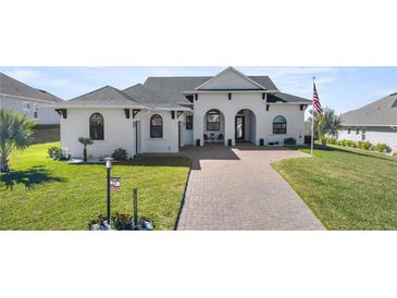 Two-story house with white walls, gray roof, and a brick driveway at 5141 Greens Dr, Lady Lake, FL 32159