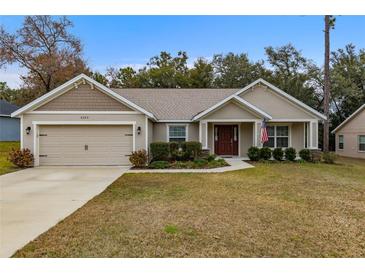 House exterior featuring a two-car garage and manicured lawn at 6303 Sw 116Th Street Rd, Ocala, FL 34476