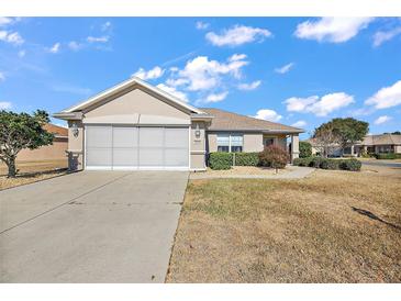 Tan one-story house with screened garage and landscaping at 14315 Se 85Th Ave, Summerfield, FL 34491