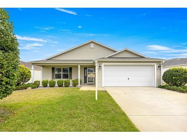 Charming single-story home featuring a well-manicured lawn, attached garage, and delightful curb appeal at 2418 Hopespring Loop, The Villages, FL 32162