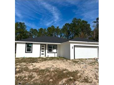 Newly constructed home with a white exterior, black accents, and a two-car garage at 2657 Sw 176Th Loop, Ocala, FL 34473