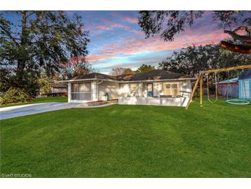 Charming single-story home with a lush green lawn, mature trees, and a front porch at 35428 Crescent Dr, Fruitland Park, FL 34731