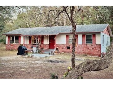 Brick ranch home with red accents, covered porch, and spacious yard at 5625 Sw 181St Ct, Dunnellon, FL 34432