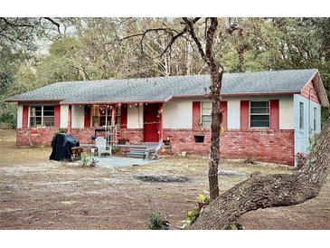 Charming single-story home featuring brick accents, red shutters, and a cozy front porch seating area at 5625 Sw 181St Ct, Dunnellon, FL 34432
