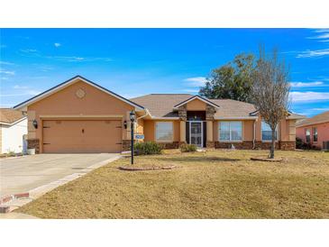 Single-story home with a two-car garage and landscaped lawn at 8217 Sw 61St Ct, Ocala, FL 34476