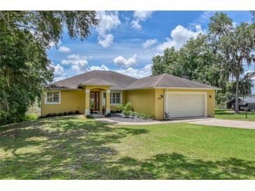 Beautiful yellow house with a two-car garage and well-manicured lawn at 10170 Se 106Th Ln, Belleview, FL 34420