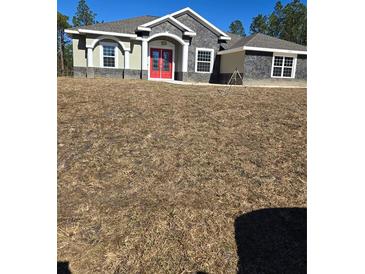 Single-story home with red double doors and stone accents at 12217 Sw 67Th Ln, Ocala, FL 34481