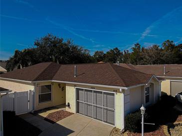 Tan one-story house with brown roof, gray garage door, and landscaped yard at 17074 Se 75Th Wickson Ct, The Villages, FL 32162