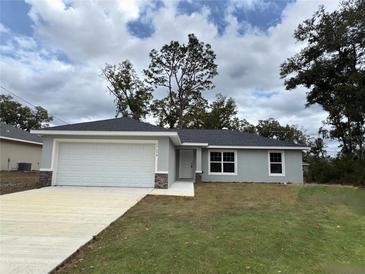 Newly constructed home with gray siding, white garage door, and landscaping at 17698 Sw 113Th Pl, Dunnellon, FL 34432