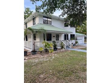 Charming two-story white home with a green roof, inviting front porch and well-maintained lawn at 10245 Sw 105Th St, Ocala, FL 34481
