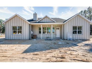 Charming new construction home featuring vertical siding, inviting front porch, and pristine curb appeal on a sunny day at 11910 Sw 43Rd Street Road, Ocala, FL 34481