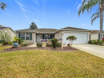 Single-story home with landscaped lawn, attached garage, and a porch at 1509 Hollyberry Pl, The Villages, FL 32162