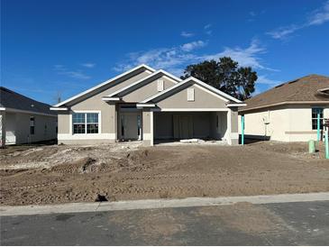 New construction home with a light beige exterior, two-car garage, and landscaping at 4429 Sw 90Th Pl, Ocala, FL 34476