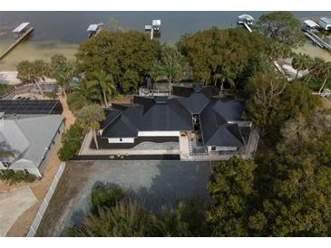 Stunning aerial view of a waterfront property featuring a unique black roof, lush landscaping, and boat docks at 13061 Se 158Th Ln, Weirsdale, FL 32195