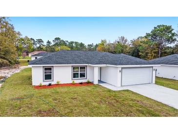 Charming single-story home featuring a gray roof, white exterior, landscaped front yard, and a two-car garage at 15294 Sw 27 Ln, Ocala, FL 34481