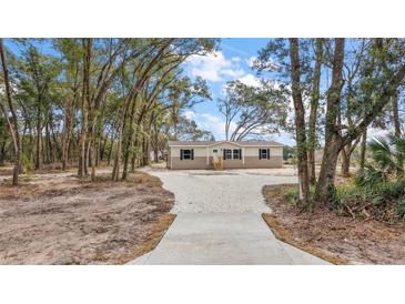 Tan mobile home with gray trim, wood steps, and a gravel driveway at 6555 Se 165Th Ave, Ocklawaha, FL 32179