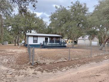 Single-story home with a spacious front porch and a fenced yard at 14497 Ne 189Th Pl, Fort Mc Coy, FL 32134