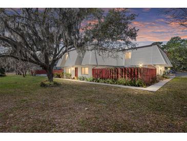 Charming townhouse with a well-maintained lawn, mature tree, and a red privacy fence at sunset at 2145 Ne 45Th Ave # 2145, Ocala, FL 34470