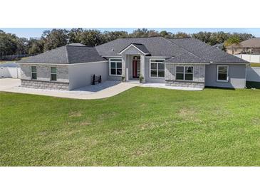 Stunning single-story home featuring a manicured lawn, gray roof, and a beautiful red front door at 6215 Se 13Th St, Ocala, FL 34472