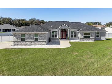 Beautiful single-story home featuring a well-manicured lawn and a striking brick and gray color scheme at 6215 Se 13Th St, Ocala, FL 34472