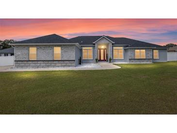 Charming single-story home featuring a well-manicured lawn, elegant brick accents, and a welcoming red front door at 6215 Se 13Th St, Ocala, FL 34472