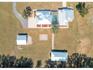 Stunning aerial view of a unique estate with a screened pool and multiple outbuildings at 7688 Se 135Th St, Summerfield, FL 34491