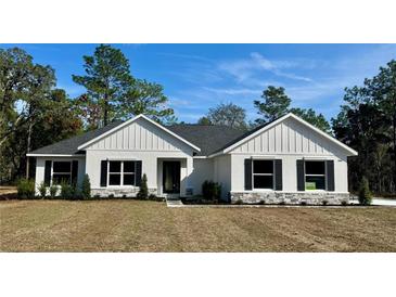 Charming single-story home featuring a well-manicured lawn, stone accents, and a welcoming entrance at 8481 Sw 137 Ct, Dunnellon, FL 34432