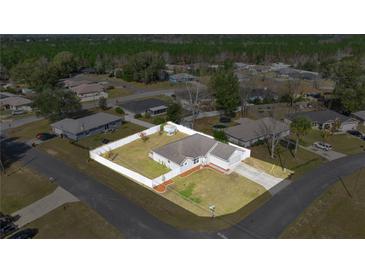 Charming single-story home with white fence, well-manicured lawn, and long driveway on a spacious lot at 2 Hemlock Terrace Trl, Ocala, FL 34472