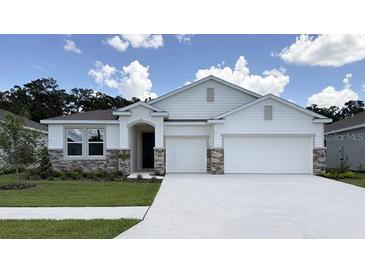 Charming single-story home featuring stone accents, a two-car garage and a well-manicured lawn at 3079 Canopy Oak Blvd, Wildwood, FL 34785
