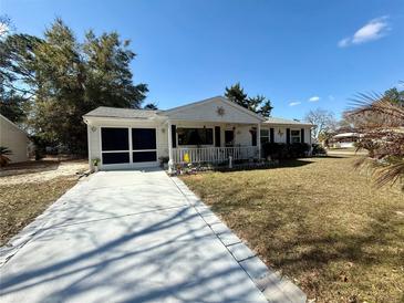 Charming single-story home with a screen garage, white picket fence and landscaped front yard on a sunny day at 10824 Sw 90Th Ter, Ocala, FL 34481