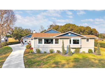 Charming single-story home featuring a manicured lawn, blue trim, and a welcoming front entrance at 11619 Lane Park Rd, Tavares, FL 32778