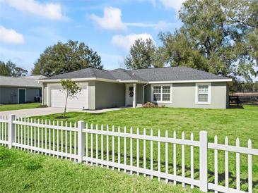 Charming single-story home with well-maintained lawn, white picket fence, and a two car garage at 14605 Sw 20Th Pl, Ocala, FL 34481