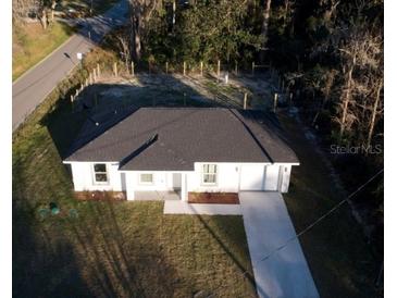 An aerial view of a newly constructed one-story home with a dark roof and a lengthy driveway at 15123 Se 63Rd Ct, Summerfield, FL 34491