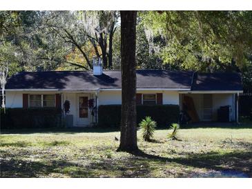 Ranch style home exterior with white walls, red shutters, and a chimney at 18800 Sw 31St St, Dunnellon, FL 34432