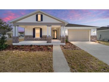 Charming single-story home featuring a covered porch with stone accents and a two-car garage at 5589 Sw 78Th Ave Rd, Ocala, FL 34474