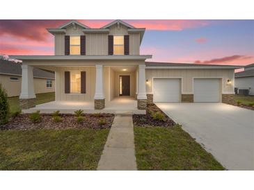 Charming two-story home with a welcoming front porch and a two-car garage and stone accents at 7821 Sw 55Th Ln, Ocala, FL 34474