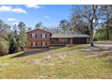 Charming two-story home featuring a well-manicured lawn and a two car garage at 8981 Sw Sw 209Th Cir, Dunnellon, FL 34431