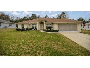 Charming home boasts a spacious front yard, beautiful landscaping, and an inviting entryway with an arched portico at 10884 Sw 53Rd Cir, Ocala, FL 34476