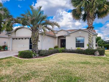 Charming single-story home with a well-manicured lawn and lush tropical landscaping, including mature palm trees at 15857 Sw 11Th Terrace Rd, Ocala, FL 34473