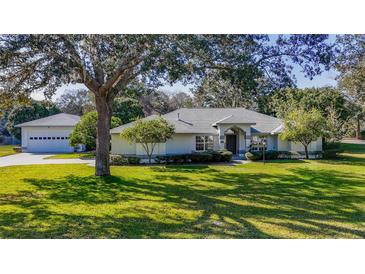 Charming single-story home with a well-manicured front yard, lush green lawn, and mature trees providing shade at 1712 Ne 40Th Ave, Ocala, FL 34470