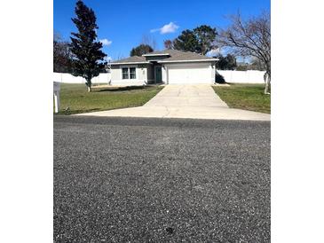 Charming single-story home with a well-manicured lawn, a two-car garage, and a new driveway at 4861 Sw 110 Ln, Ocala, FL 34476