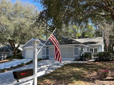 Charming single story home with tidy landscaping, an American flag and a brick driveway at 8045 Sw 115Th Loop, Ocala, FL 34481