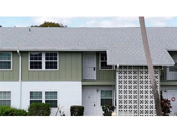 Two-story condo building featuring a pale green and white facade and a light gray shingle roof at 840 Center Ave # 98, Holly Hill, FL 32117