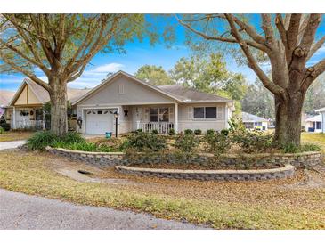 Charming single-story home features a manicured lawn, stone retaining wall, and an attached garage at 9691 Sw 95Th Ct # D, Ocala, FL 34481