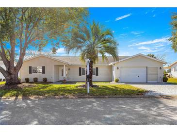 Charming single-story home with lush landscaping, palm tree and an attached two-car garage at 9884 Se 175Th Pl, Summerfield, FL 34491