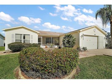 Charming single-story home features a screened porch and well-maintained landscaping under a bright, partly cloudy sky at 2538 Privada Dr, The Villages, FL 32162